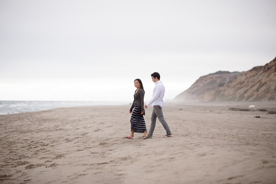 Couple walking along the beach in front of a dreamy misty haze