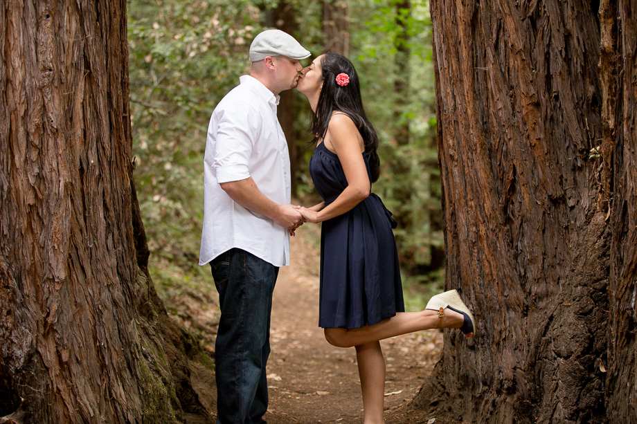 Couple kissing on hiking trail between two redwood trees at Huddart Park in Woodside