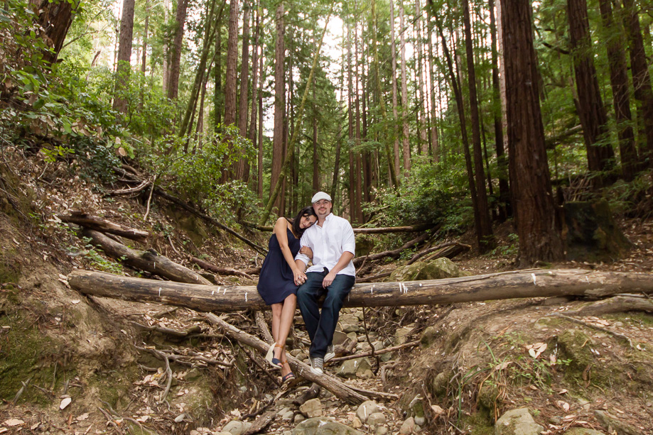 Couple sitting on log across dry creek in the woods Woodside