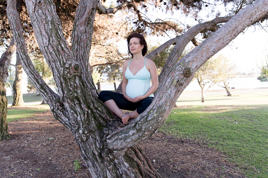 Expectant mother sitting in a tree holding tummy