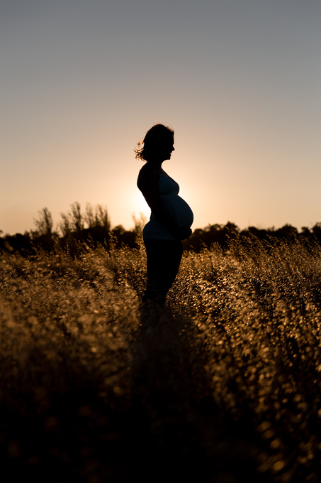 Silhouette shot of sun at sunset behind pregnant mother