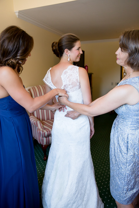 Mother of the bride and maid of honor helping bride with her wedding dress