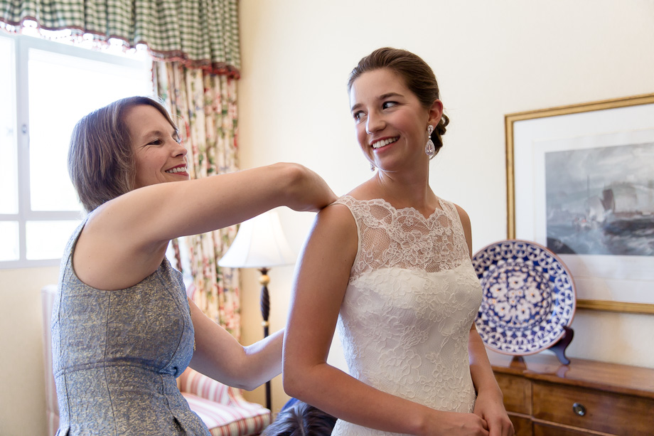 Mother of the bride helping her daughter with the wedding gown