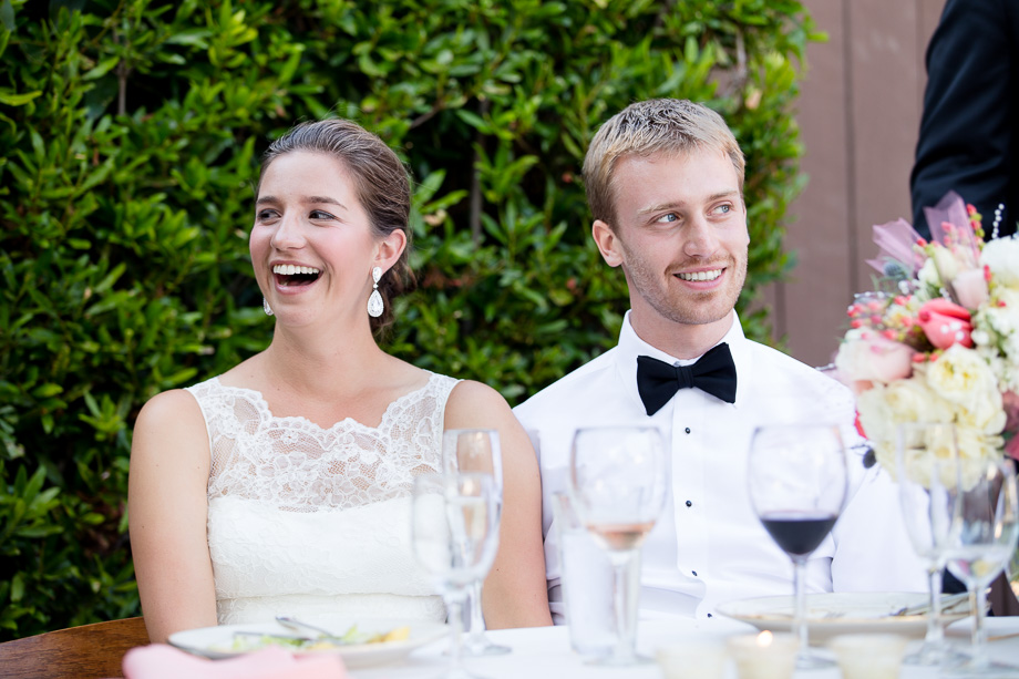 Bride and groom at the head table enjoying and smiling at guests