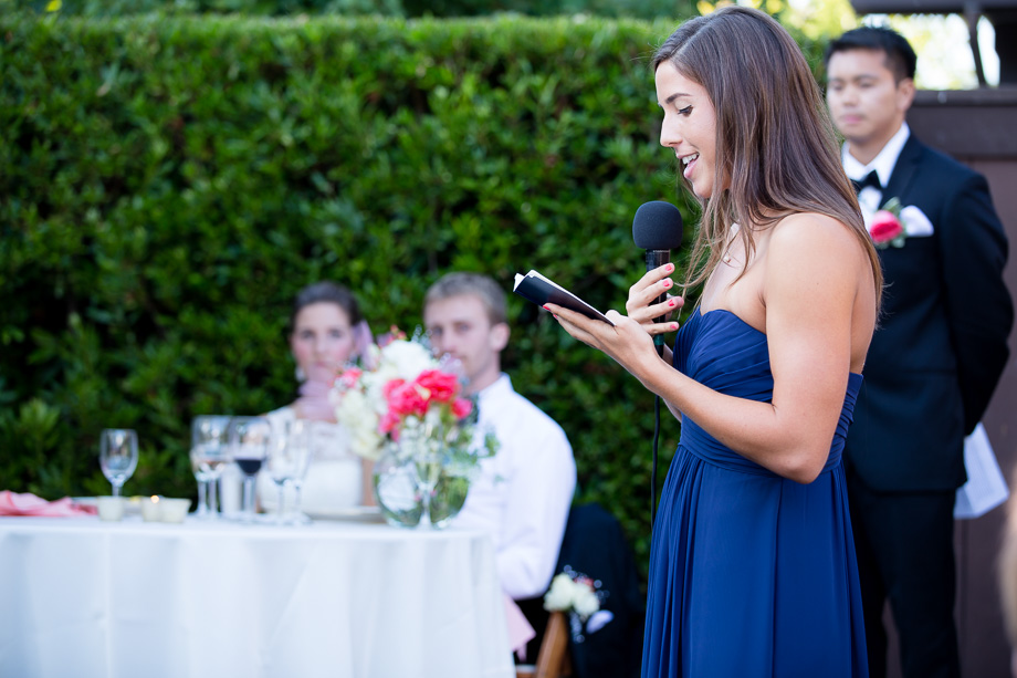 Maid of honor giving toast while the bride and groom watch