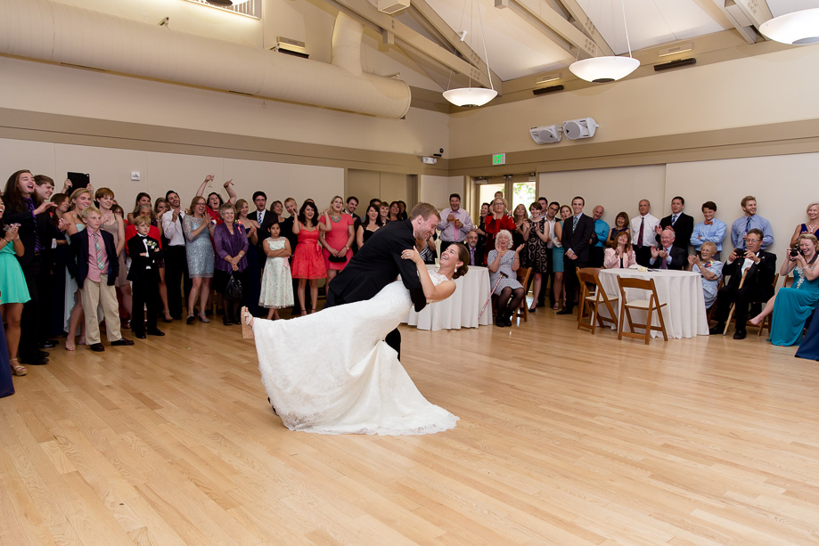 Newlywed couple doing the dip on their first dance with guests watching in a circle at Ladera Oaks