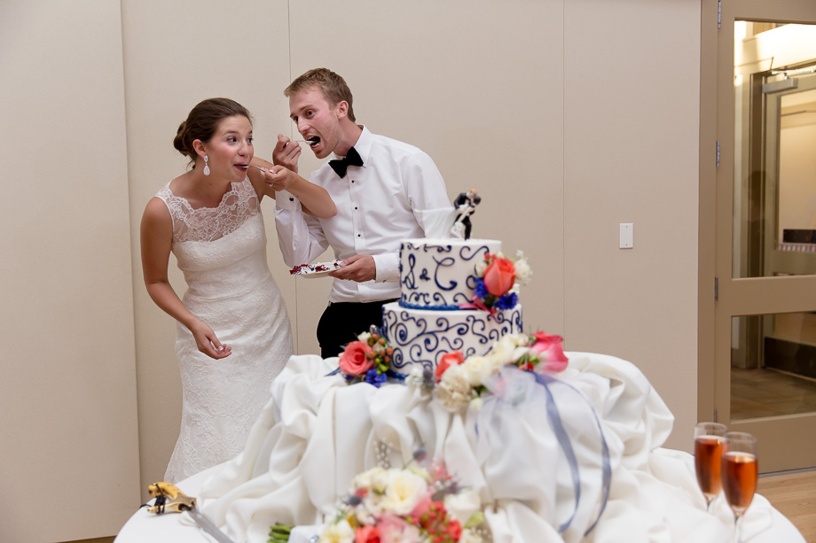The newlywed couple feeding themselves a piece of wedding cake