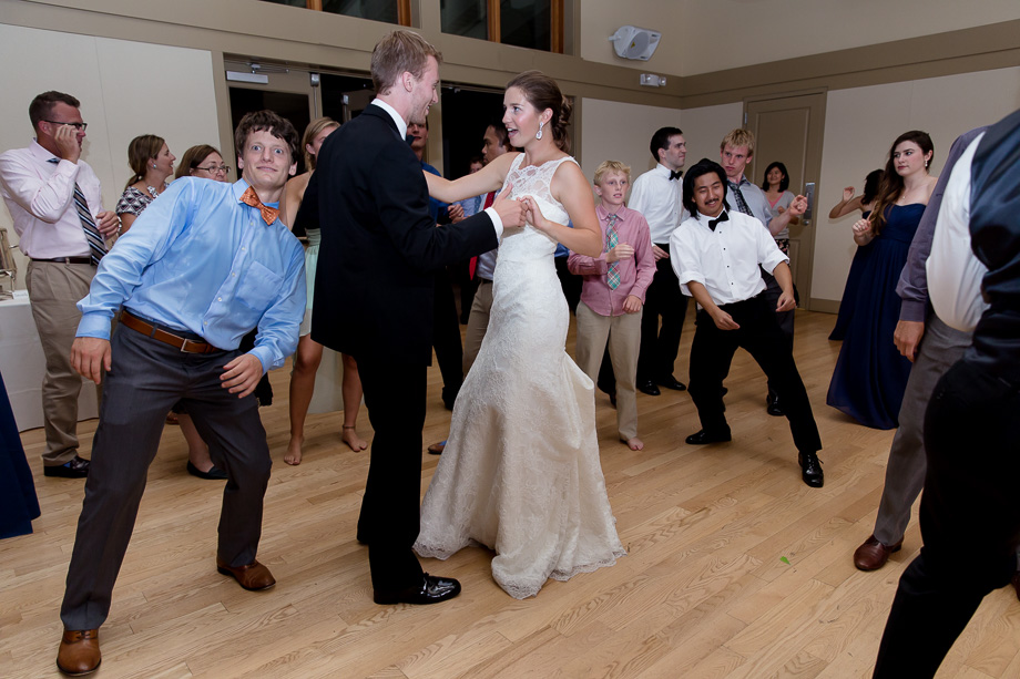 Bride and groom dancing next to a photobomber during wedding reception