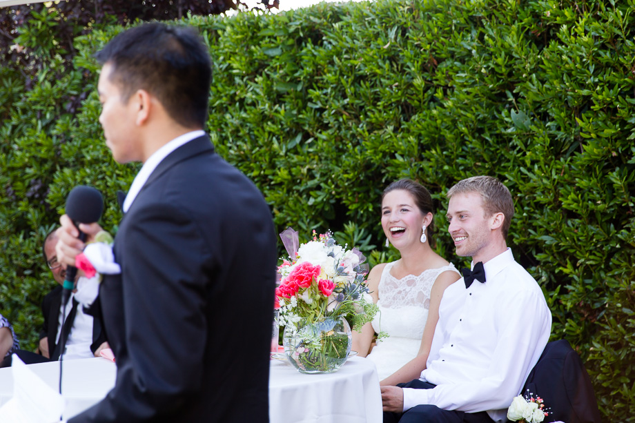 Bride and groom watching and laughing at the best mans funny speech