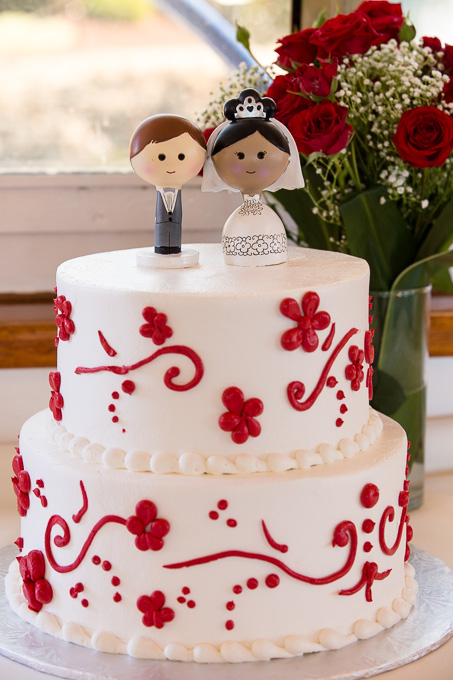 cute wedding cake with adorable bride and groom cake topper, roses in background