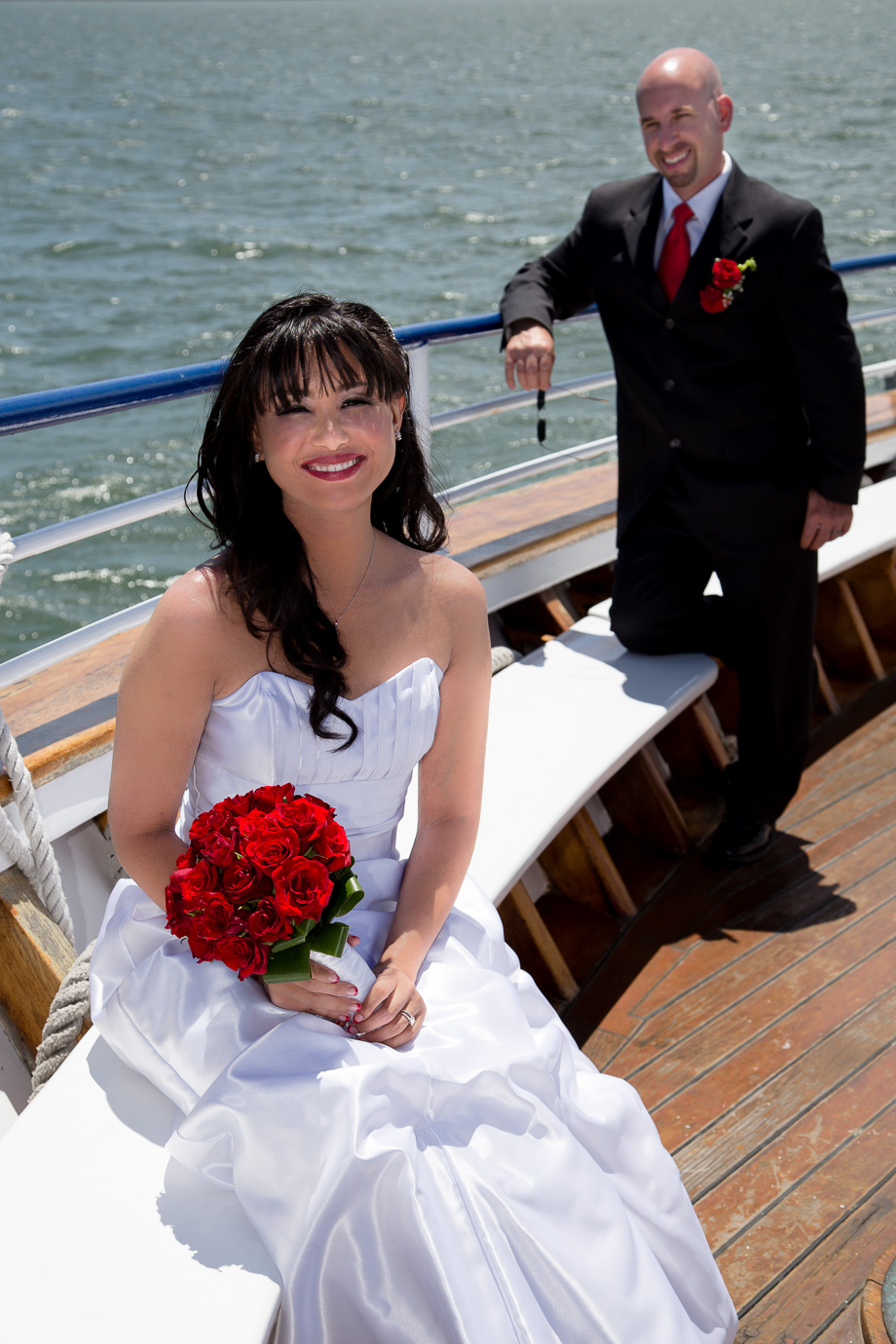 bride holding a bouquet on the Commodore Hornblower cruise boat while groom looks on