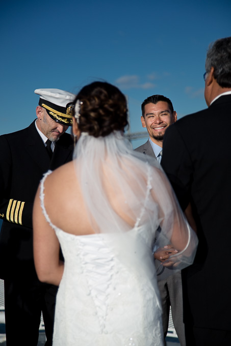 Groom peeking down the aisle between bride and her father