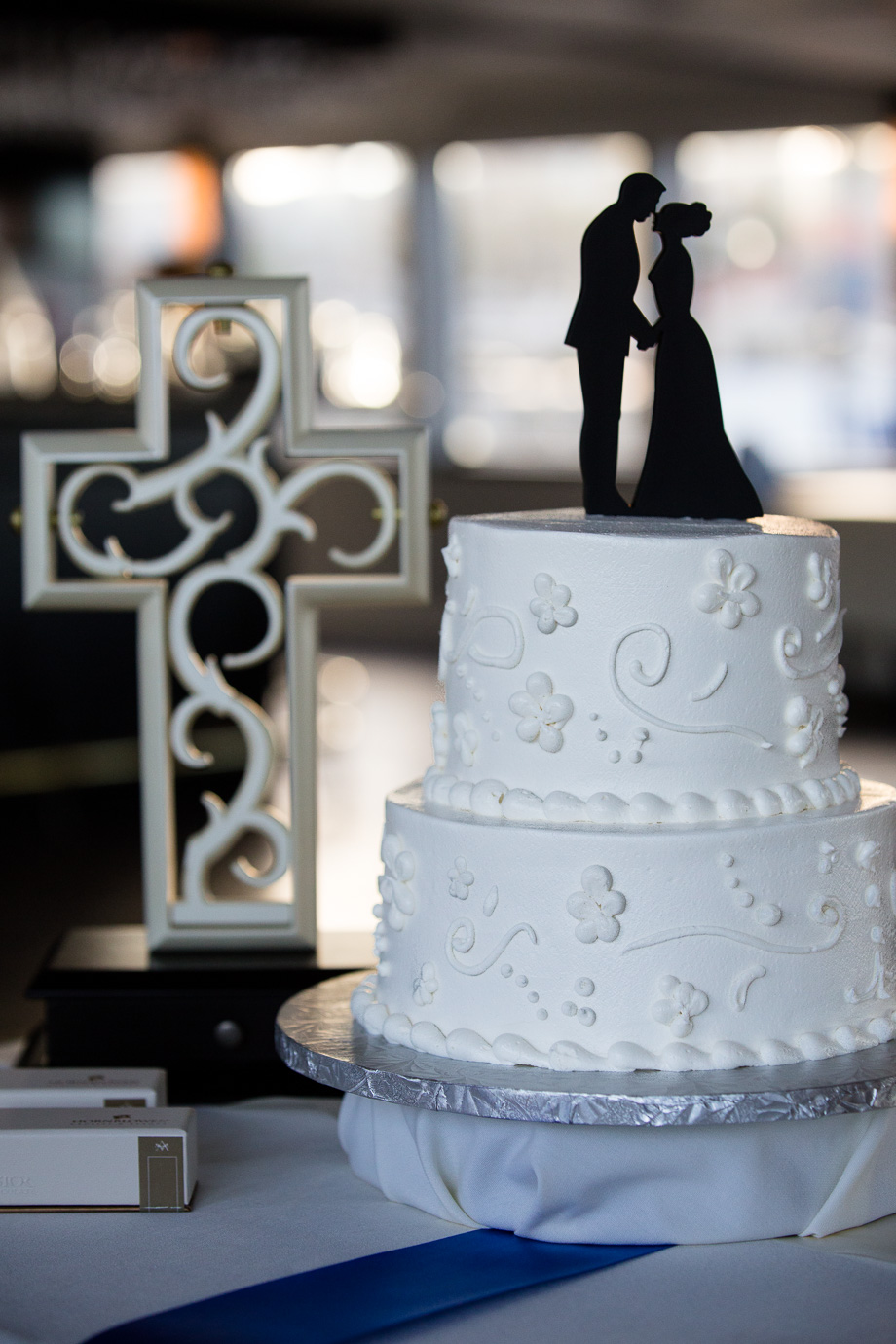 Wedding cake with silhouette cake topper and cross in background
