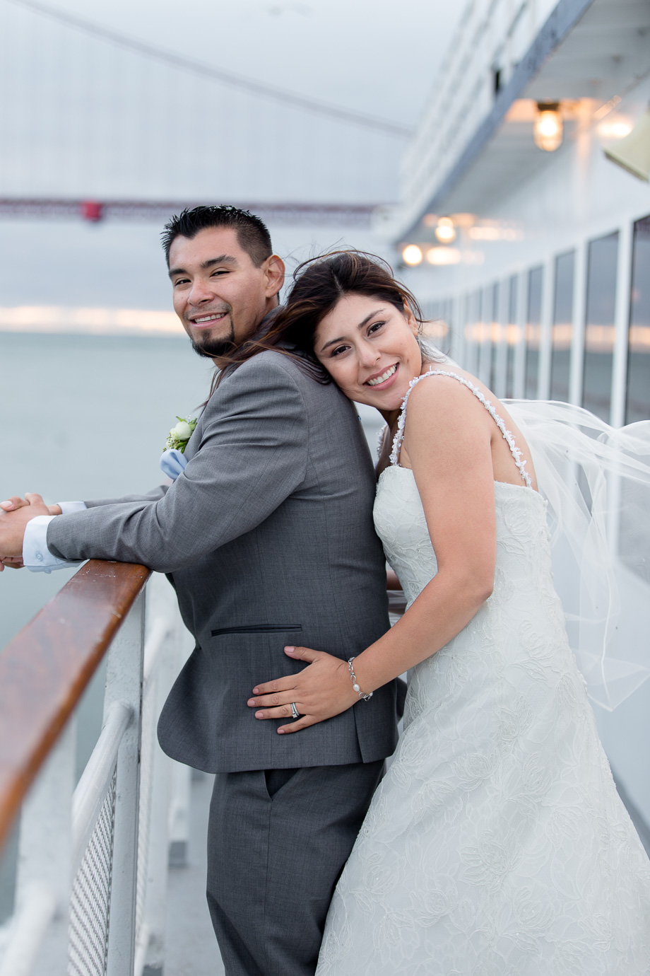 Portrait of bride behind groom on California Hornblower cruise ship with Golden Gate Bridge in the background
