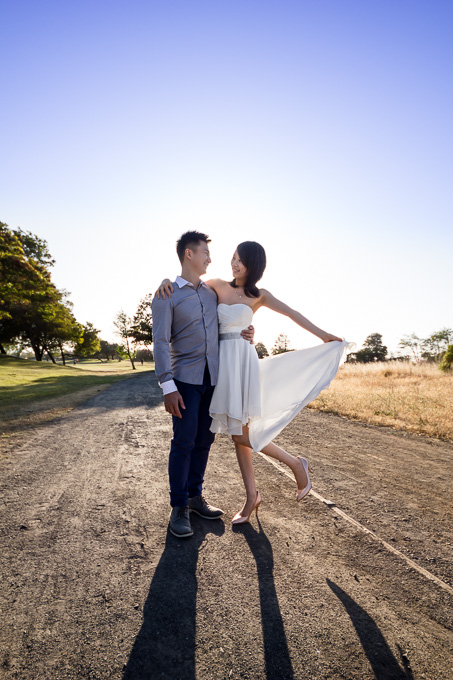 sun backlit photo of couple dancing on a dirt path with loose white dress
