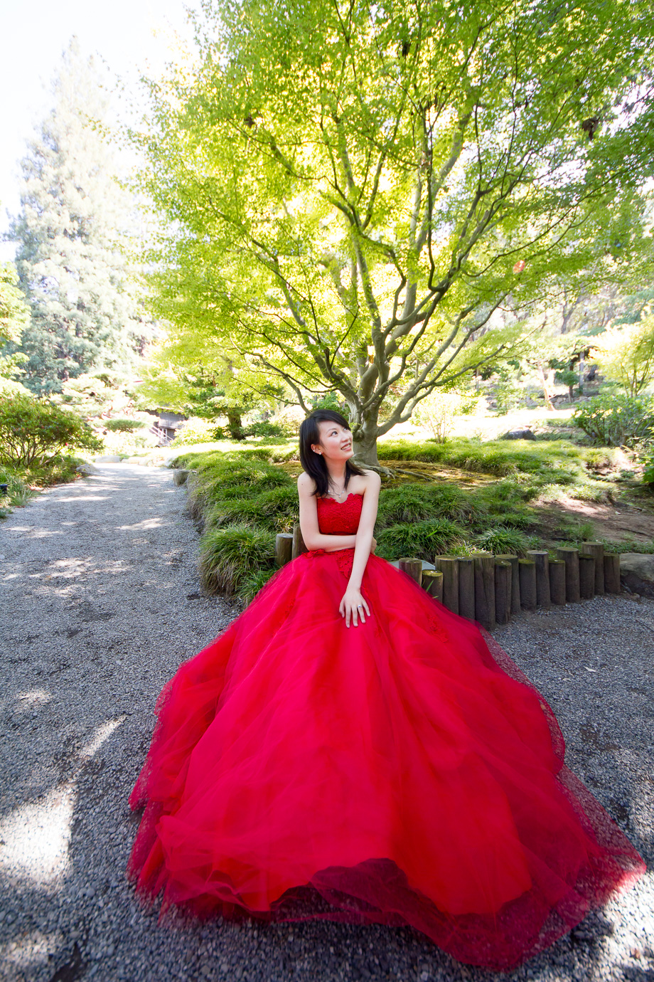Long, flowing red dress under green trees at Hakone Japanese Gardens