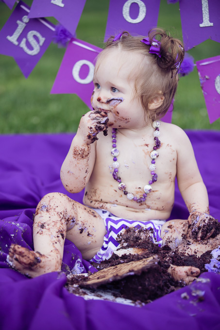Baby covered in pieces of cake after cake smash