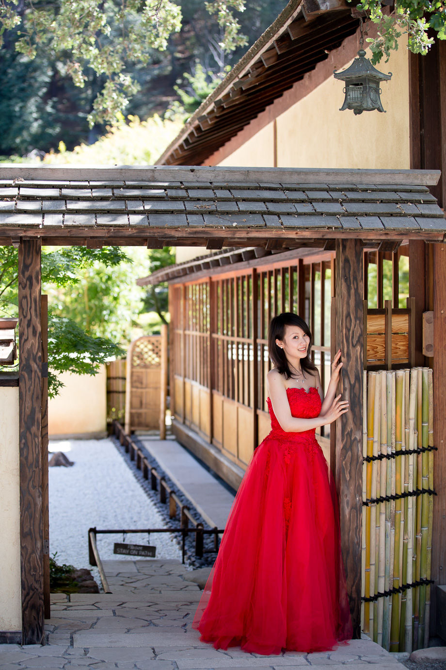 Renee in a sharp red dress leaning on a Japanese-style doorway at Hakone Gardens
