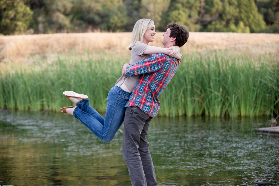Engagement photo of girl being picked up with her feet kicked out