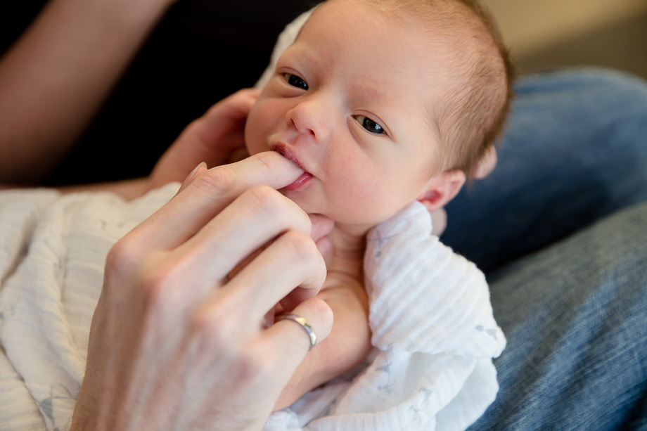 newborn baby sucking on dads index finger