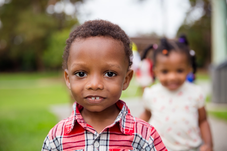 close-up of little boy with his sister behind him in the park