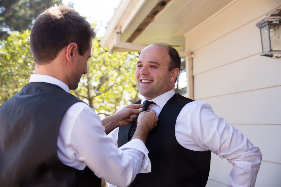 Groomsman adjusting grooms tie