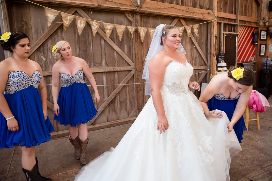 Bridesmaids helping bride ready her dress