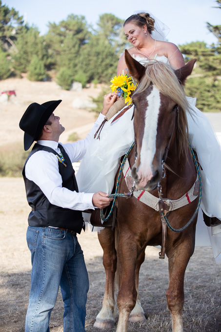 Bride riding horse while looking at groom standing on the ground