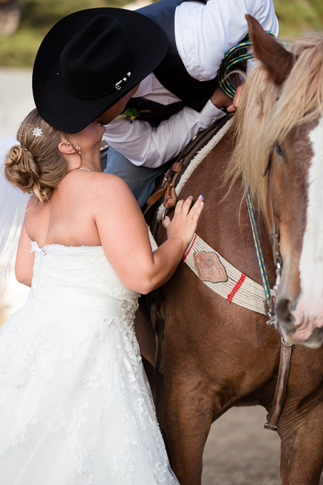 Bride and groom kissing on horse
