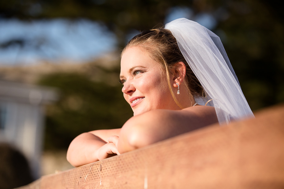 Bride leaning on fence looking off into the sunset