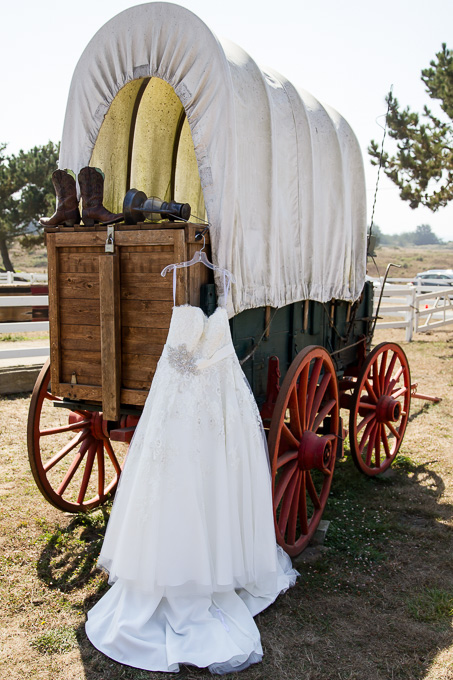 Wedding dress and boots hanging on antique wagon outside country barn