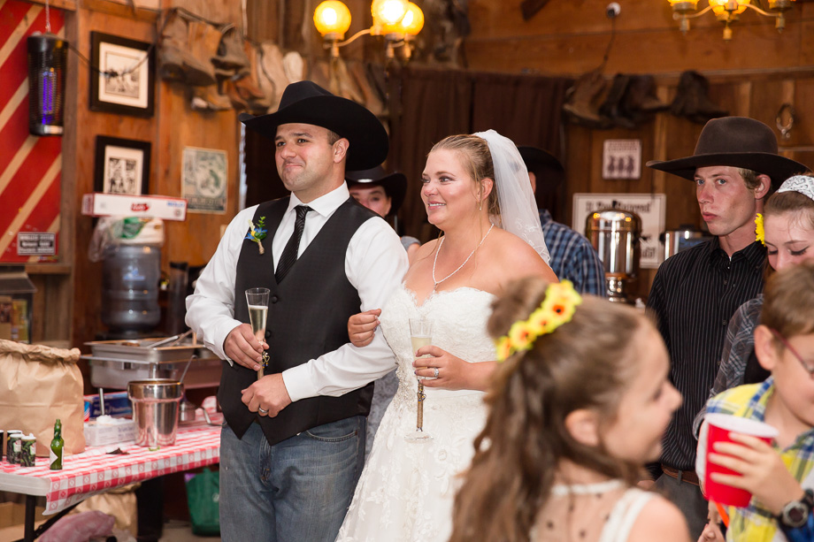 Bride and groom listening to toasts at indoor barn wedding reception