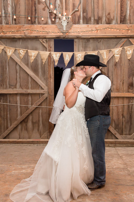 Bride and groom kissing during first dance in front of their barn door