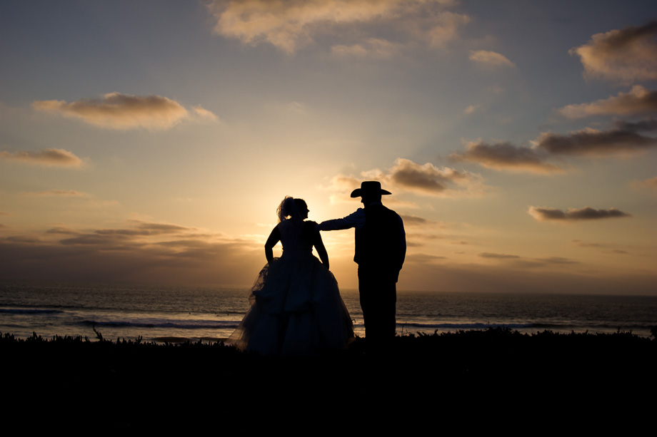 Quiet beach silhouette photo of the bride and groom looking off into the sun setting over the ocean