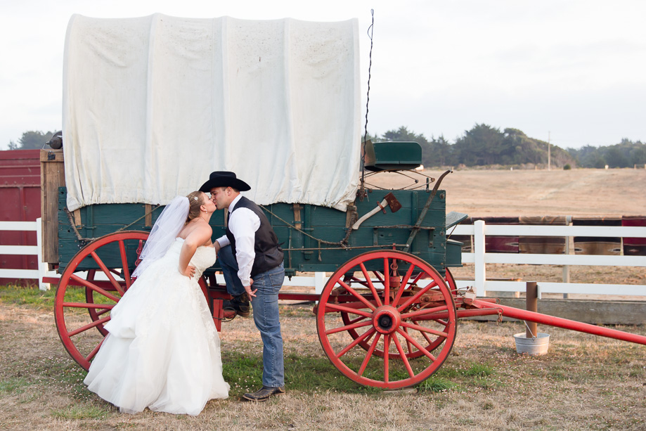 The lovely couple kissing in front of the old country wagon near the barn at Chanslor Ranch
