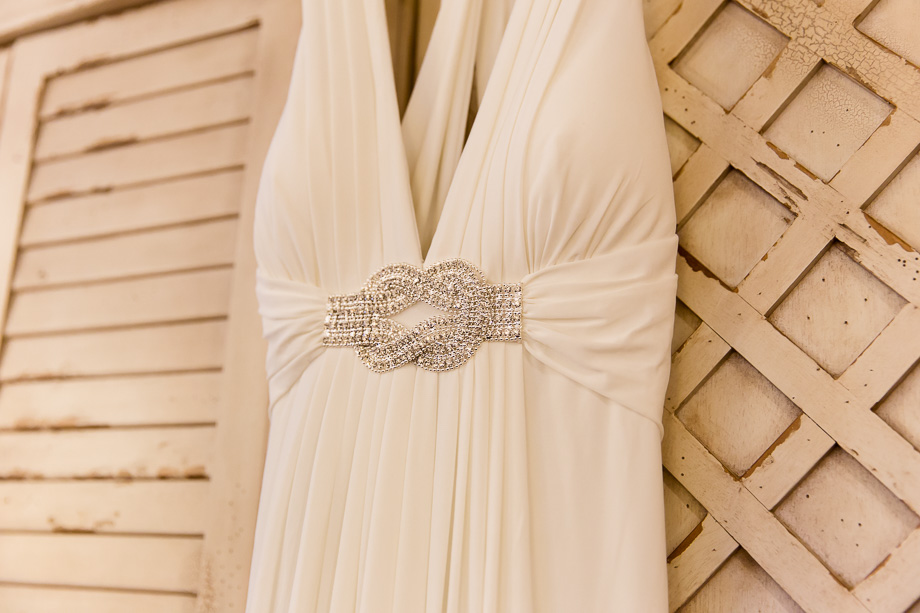 Sleek wedding gown hanging on a rustic white cabinet
