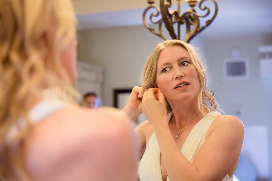 Bride adjusting her earrings before leaving for the first look