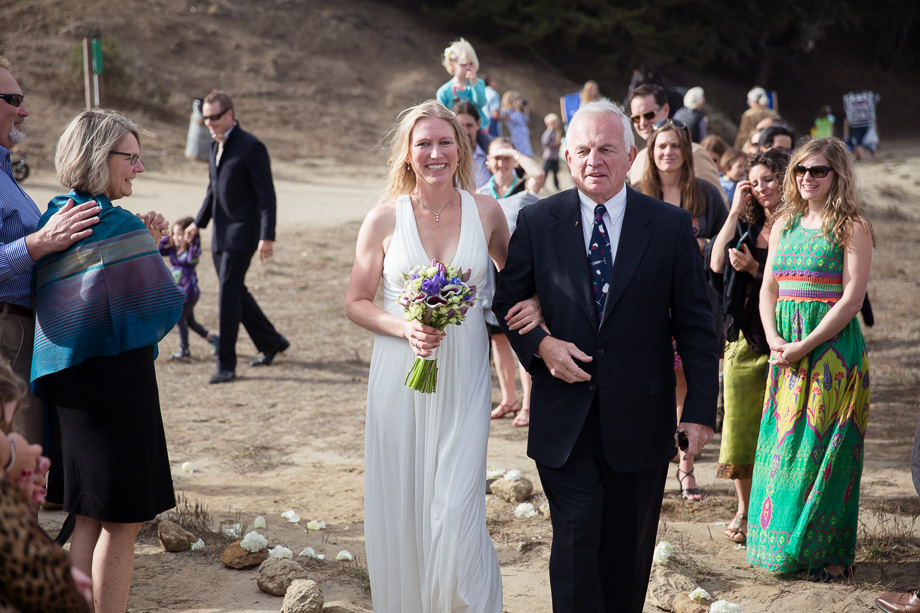 Brides father walking her down the beach aisle on her wedding day
