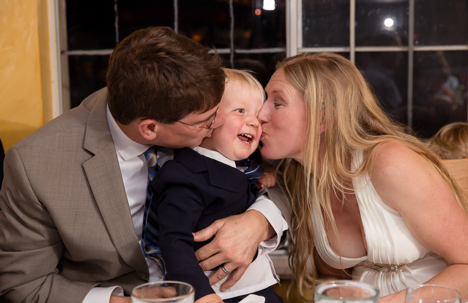 Bride and groom kissing their son at the reception at Mezzaluna restaurant