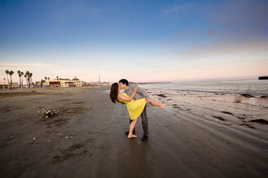 fiance and fiancee kissing on the Santa Cruz beach by the ocean and boardwalk