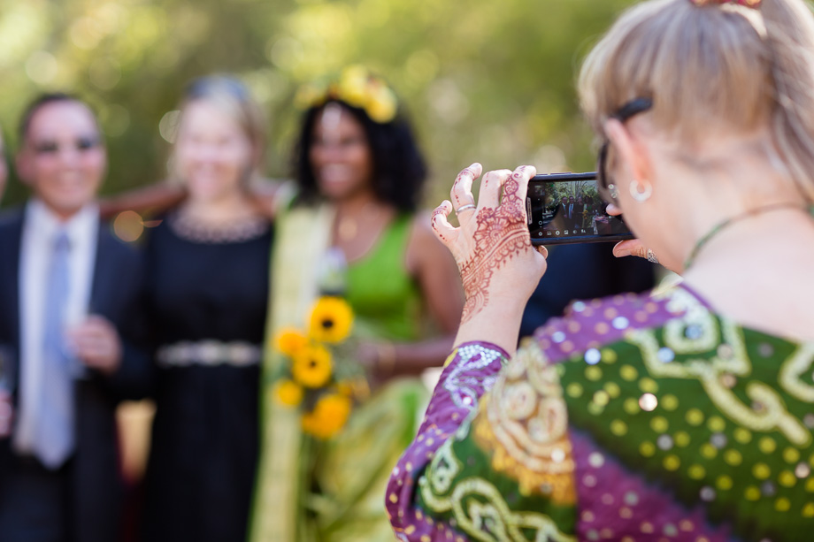 wedding guest taking a photo of the bride and guests with her cell phone
