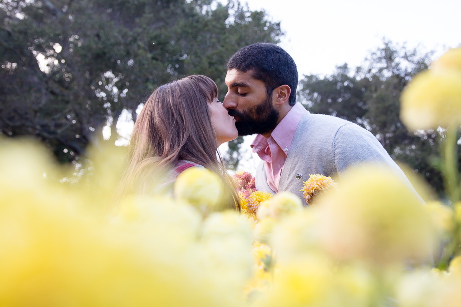 couple kissing behind yellow flowers at Gamble Garden