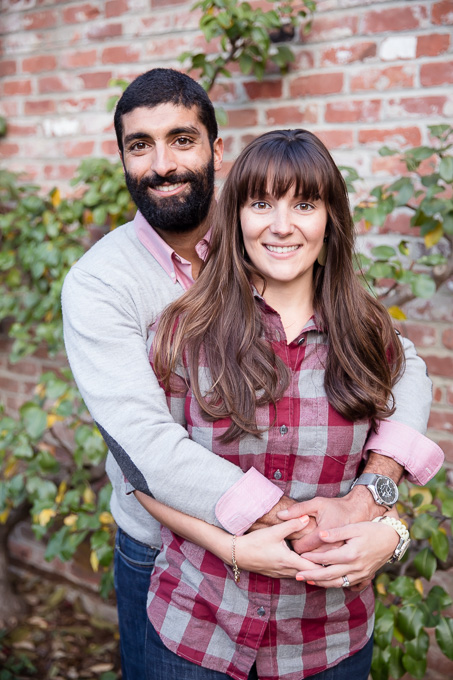 portrait of couple in front of red brick wall at Gamble Garden