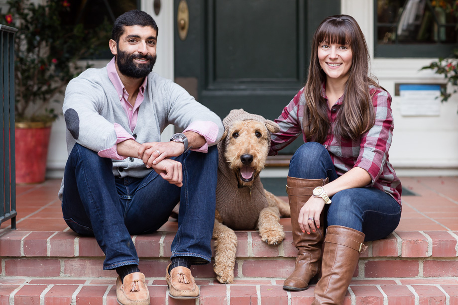 married couple sitting on red brick stairs with dog laying down between them