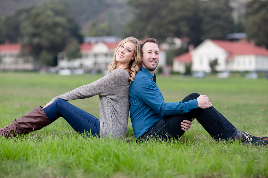 engagement photo of couple sitting back-to-back on the Cavallo Point lawn