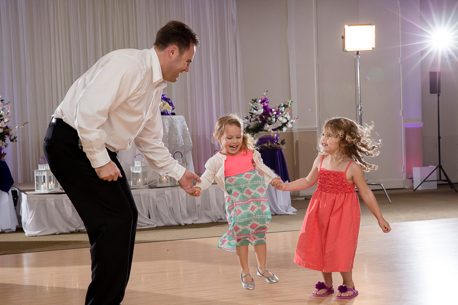 wedding guest leading two little girls to jump and dance in the reception hall at Boundary Oak Golf Club