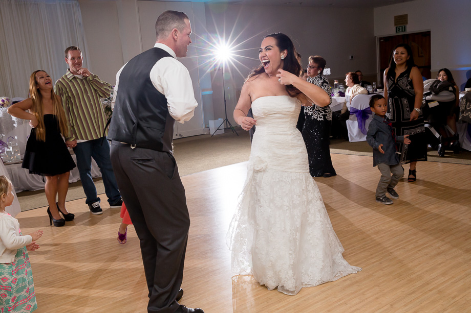 bride and groom laughing and dancing while guests look on around them
