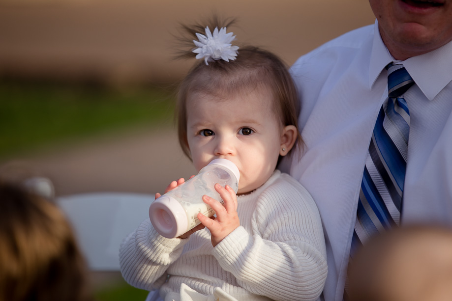 adorable little guest holding a milk bottle at the wedding ceremony