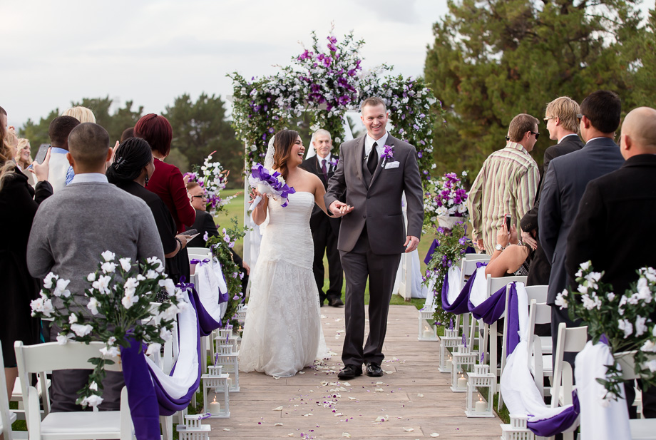 Happy couple pronounced as husband and wife under a purple arch at the Boundary Oak Golf Club