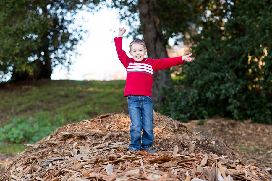 Happy boy jumping on a pile of wood chips
